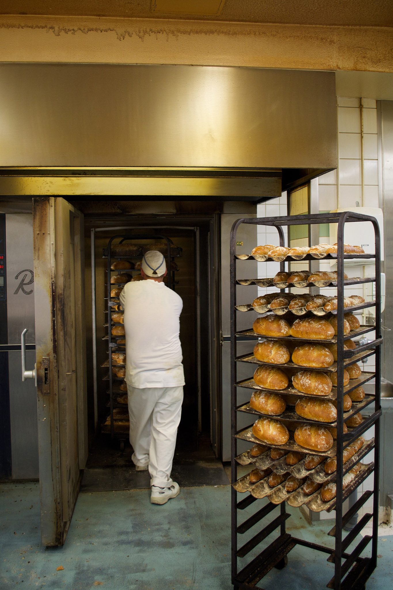 Panadero cargando un carro de panes en un horno rotativo